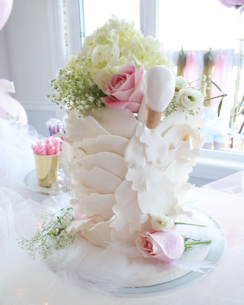 Elegant white swan princess first birthday cake adorned with fresh flowers - Kids Birthday Party Inspiration - Girls Birthday Party Ideas