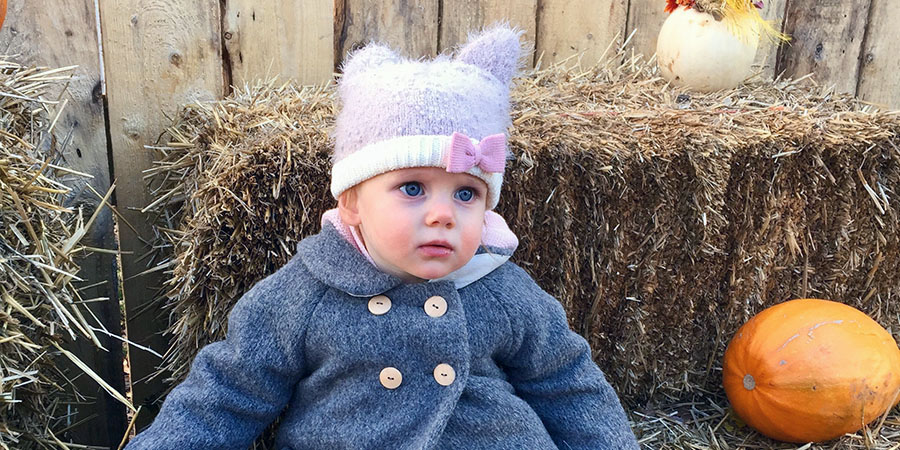 Baby sits on hay bale