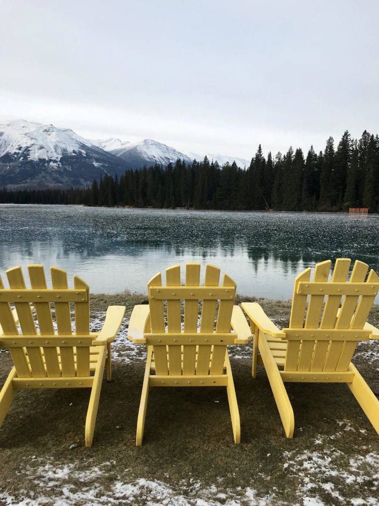 A stunning view of yellow chairs at Lake Beauvert while attending Christmas in November at Fairmont Jasper Park Lodge 