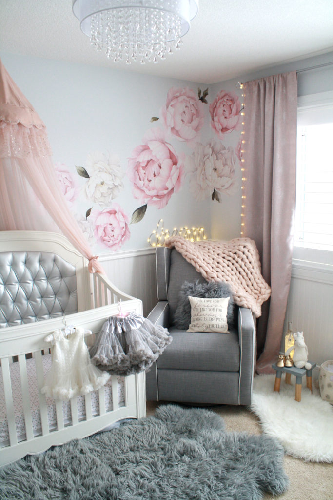 Pink and gray nursery with silver crib, peony decals and sheepskin rug