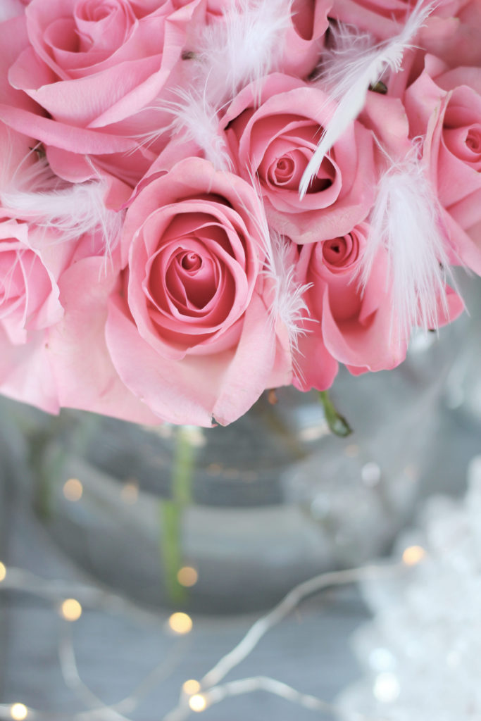 Pink roses with white feathers and twinkle lights 
