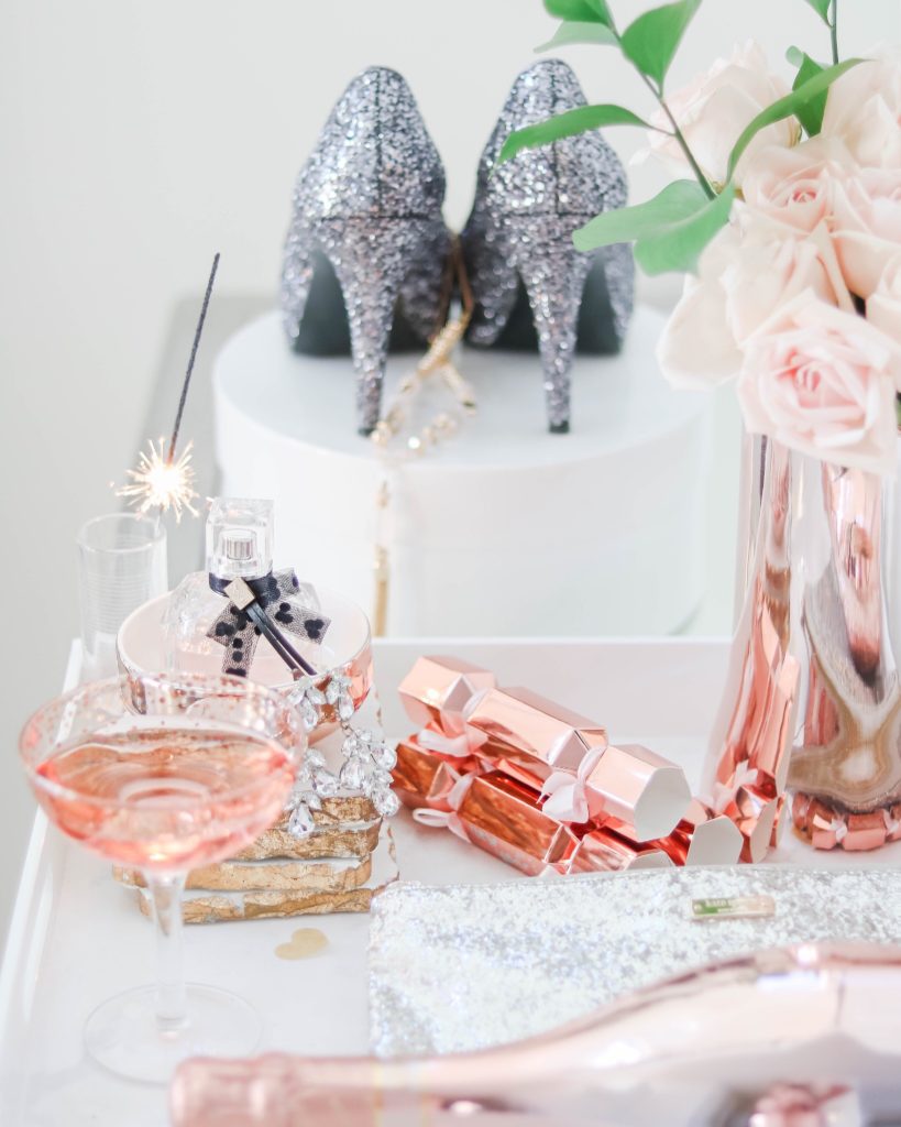 New Year's Eve styled vanity with sparkly heels, sparkling rosé , perfume and fresh roses
