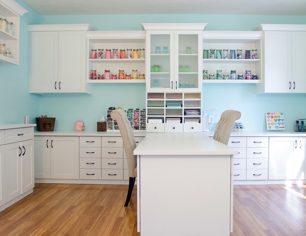 Light, bright white and teal kids craft room with organized storage cabinets and desk.