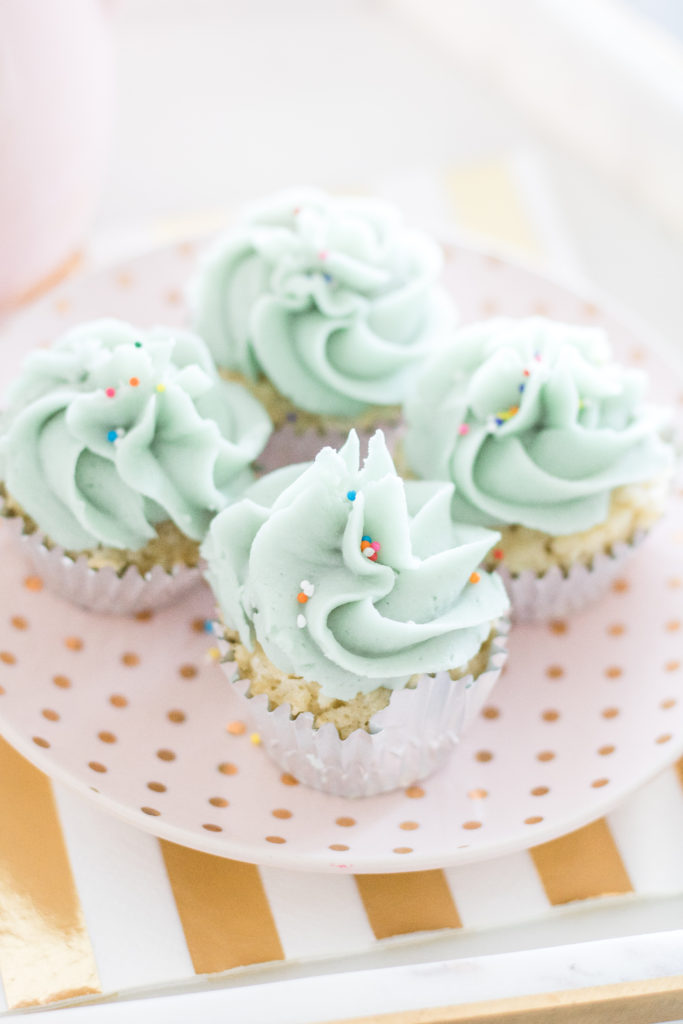Baby blue piped cupcakes with sprinkles of a pink and gold tea cup