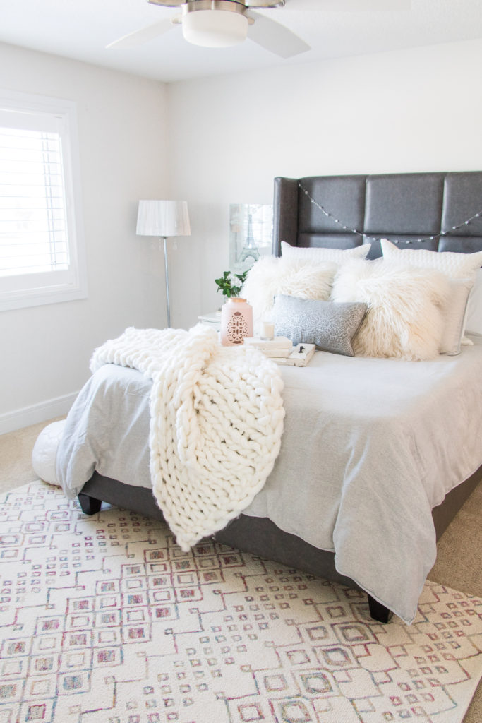 Bright and cozy master bedroom with gray duvet cover, gray leather bed, white merino wool blanket, white window shutters and cozy blanket- gray, white and pink bedroom ideas