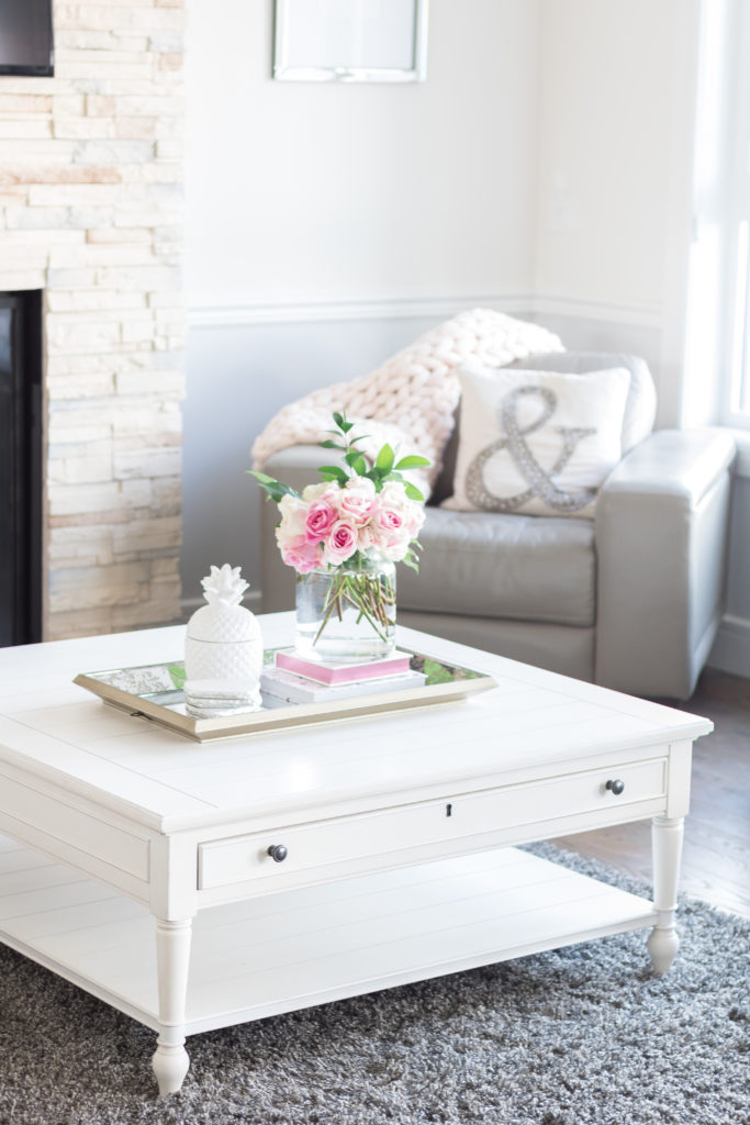 Universal Furniture Summer Hill Lift Top Cocktail Table in Cotton adorned with fresh pink roses and feminine, glam decor. White living room coffee table ideas.