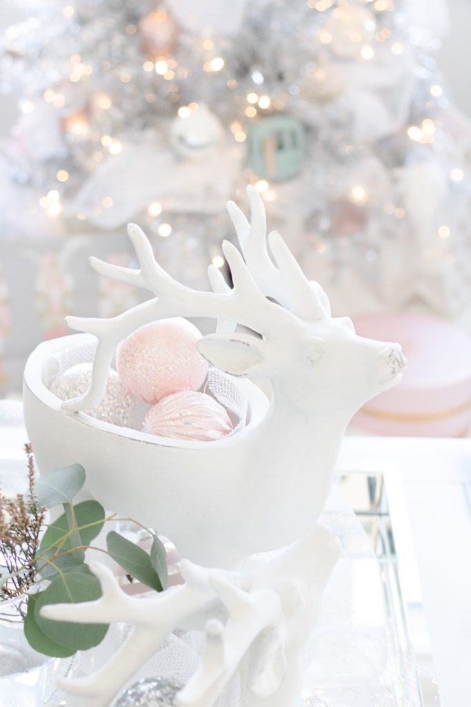 White reindeer coffee table Christmas decor with pastel Christmas ornaments and white and silver ombre Christmas tree, white Christmas coffee table decor, pink Christmas coffee table decor