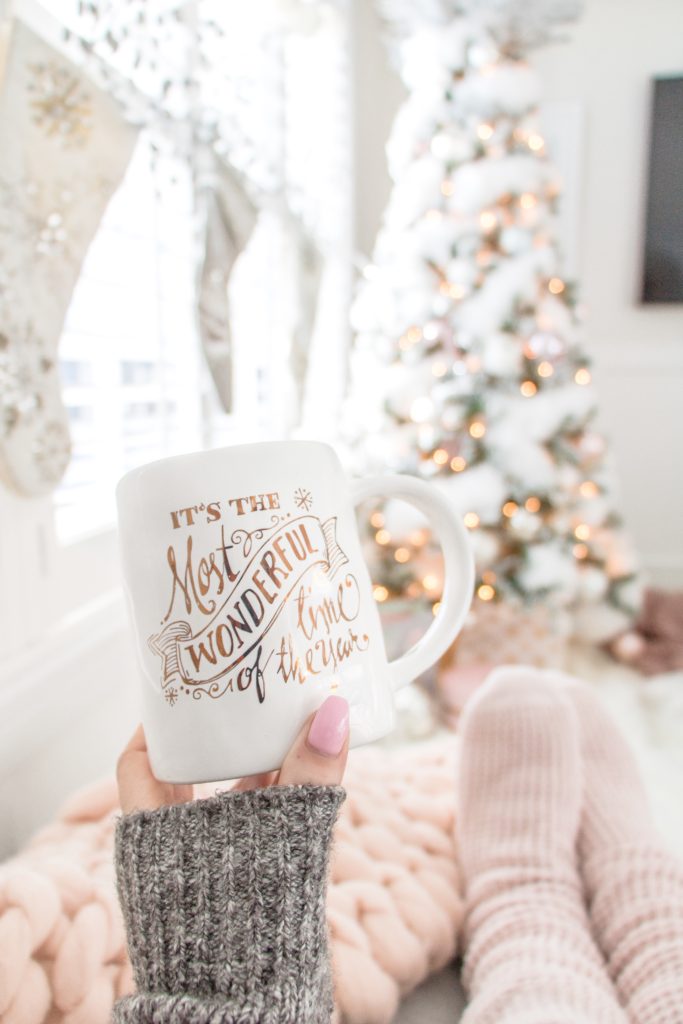 Feminine Cozy Christmas Loungewear, relaxing with a coffee in cozy pink slipper socks with a glamorous pink and white Christmas tree