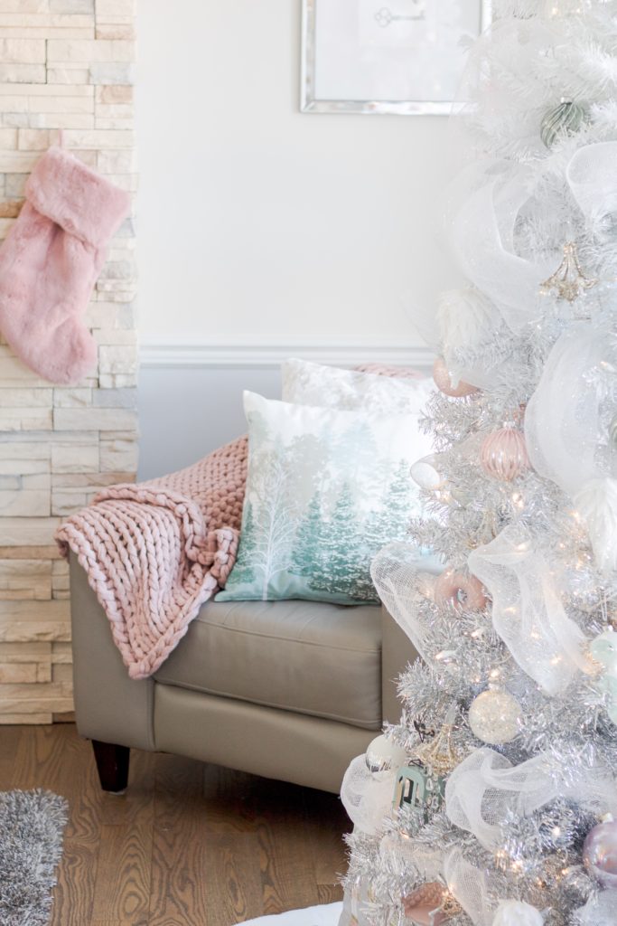 Pastel Christmas decor with pink cozy knit blanket, pink fur stockings, white ombre Christmas tree and blue pastel Christmas pillows
