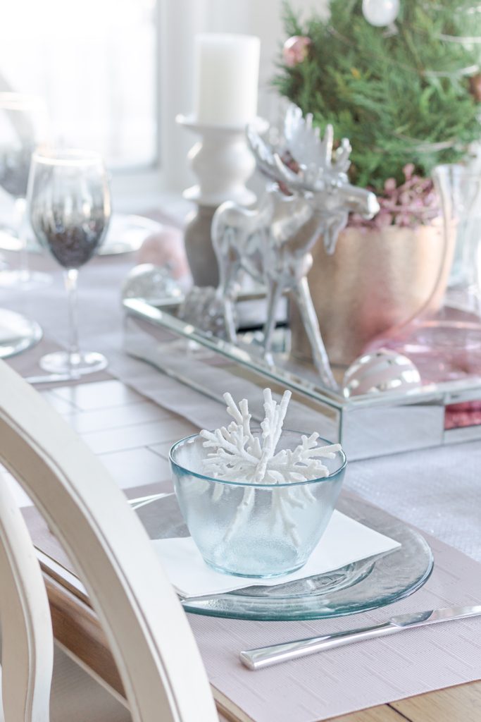 White pink and silver Christmas table setting with silver reindeer and pink placemats