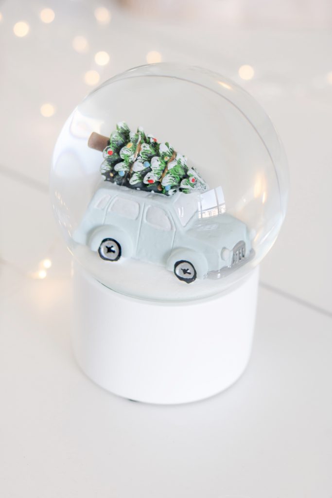 White snow globe with a pastel blue car carrying a Christmas tree - Holiday Haul Snow Globe from Urban Barn - Pastel Christmas Decor