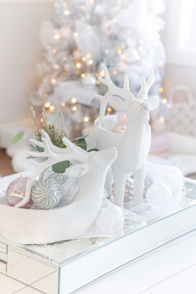 Christmas coffee table decor ideas : white reindeer planters filled with pastel pink and blue Christmas ornaments with twinkling white Christmas tree in the background