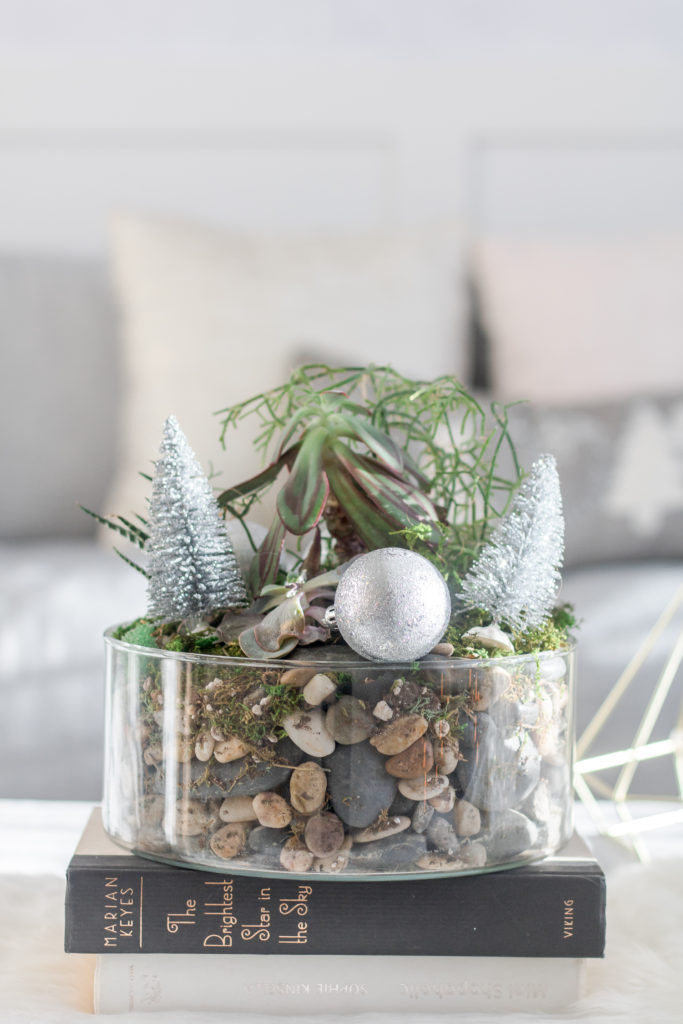 Holiday terrarium with succulents and silver Christmas decor and bottle brush trees