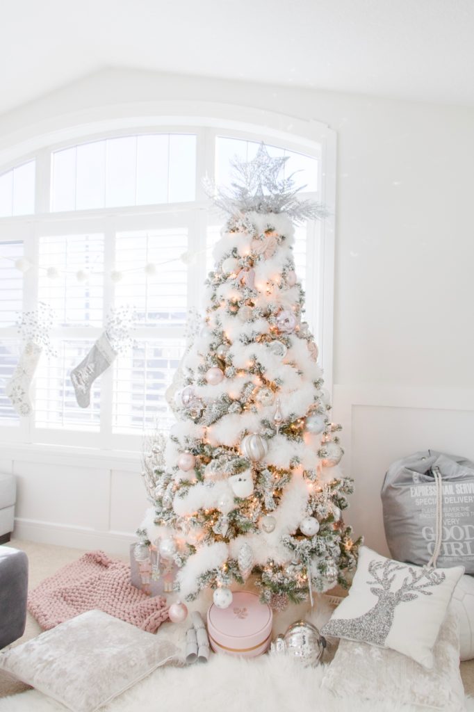 a Christmas tree decorated with white and silver ornaments, lights and  fluffy fur garlands p…