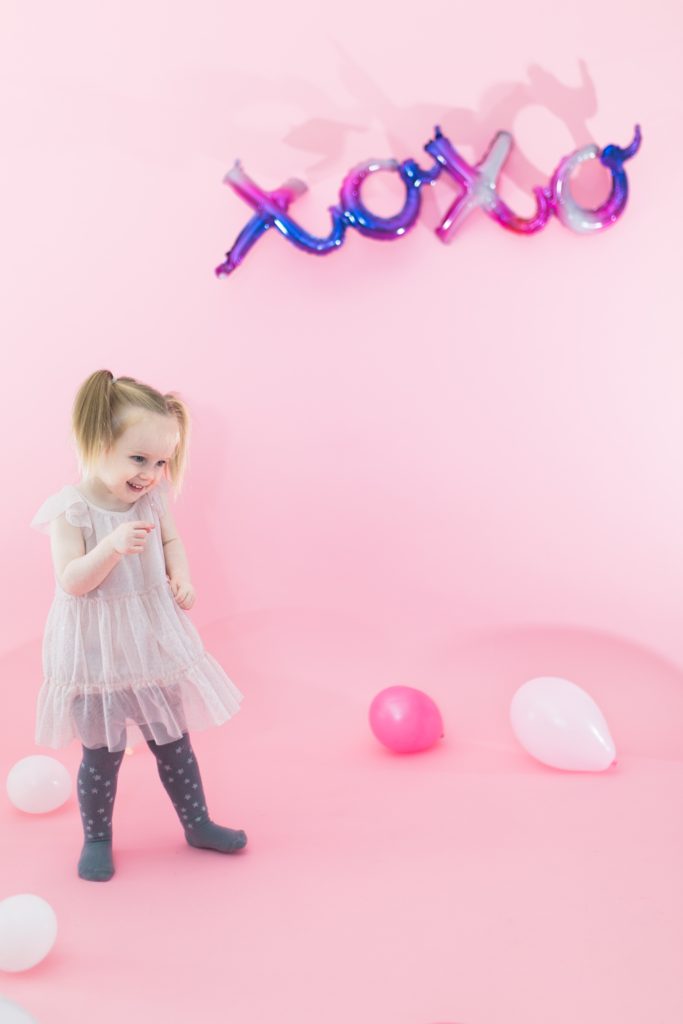 Toddler Valentine's Day mini session with pink backdrop and xoxo balloons - Cute Valentine's Day outfits for little girls, little boys and women - Valentine's Day outfit inpso