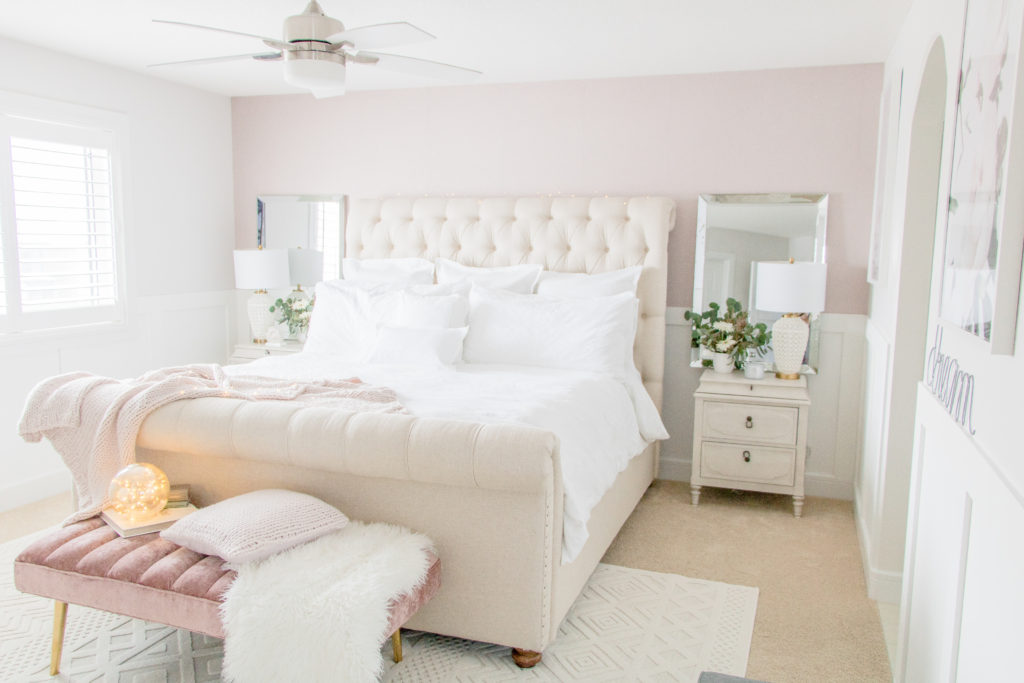 Glamorous bedroom design ideas: Feminine master bedroom with classic white bedding, pink wallpaper, pink velvet bench and neutral sleigh bed 