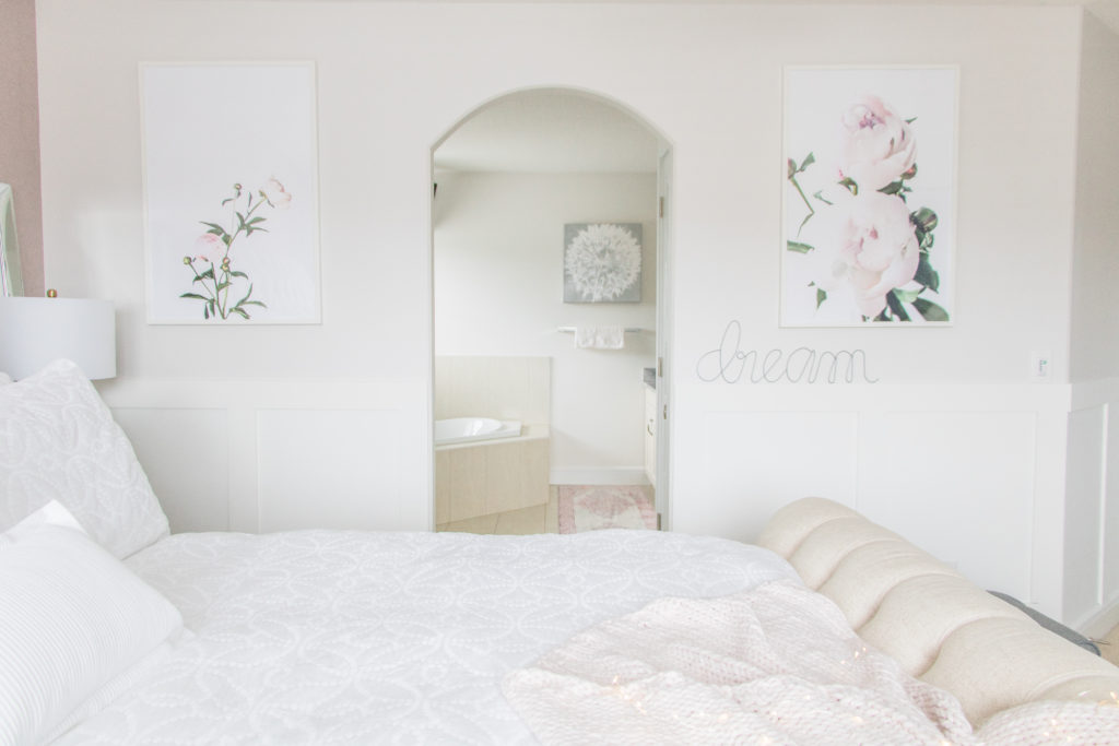 Luxurious master bedroom with pink peony artwork, white bedding and neutral furnishings 