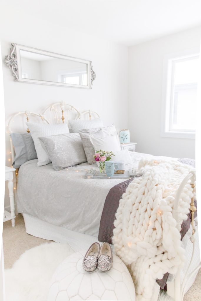 White and gray airy guest bedroom with a wrought iron bed frame and vintage inspired furniture on Chandeliers and Champagne