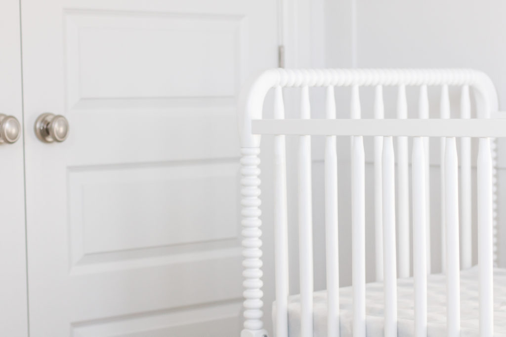 White crib with carved spindles is a focal point in this white and gray gender-neutral nursery - wWhite and grey gender-neutral nursery inspiration