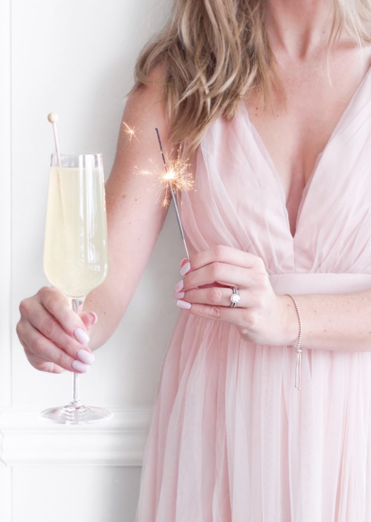 Woman in pink dress holding french 75 cocktail
