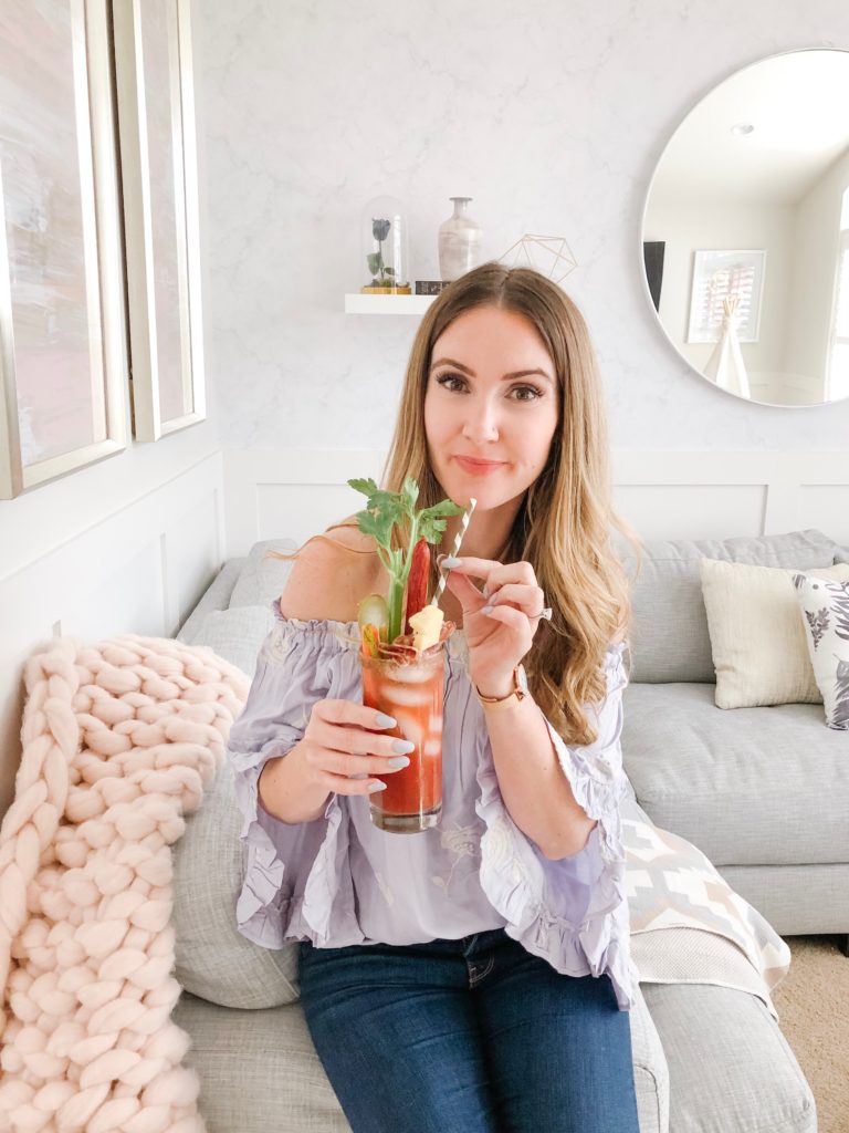 Chandeliers and Champagne blogger Holly Hunka drinking her spicy gin caesar
