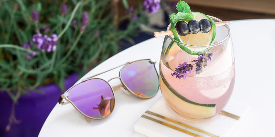 Prickly Pear Vodka Soda sitting on a patio table next to sunglasses