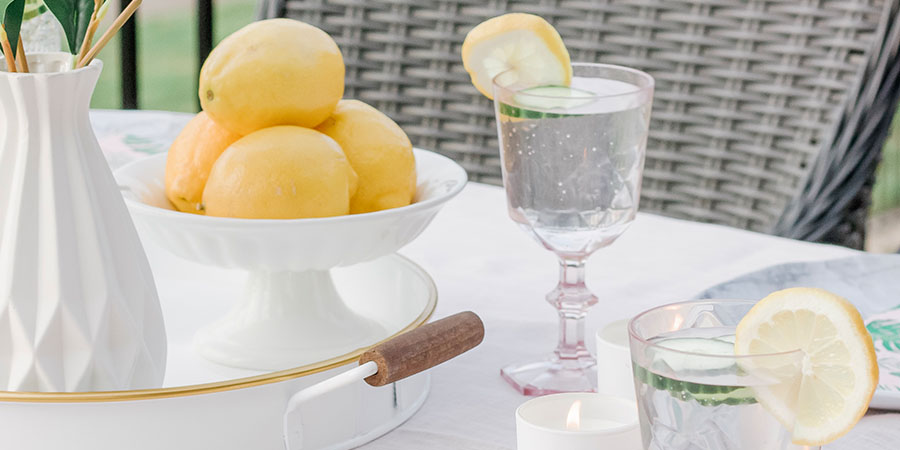 Easy outdoor table setting with fresh lemons, pink glassware and marble plates