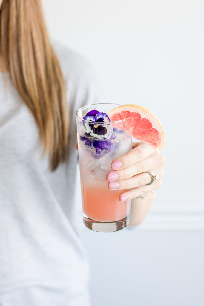 Layered Grapefruit and Rose Vodka Soda being held by a woman