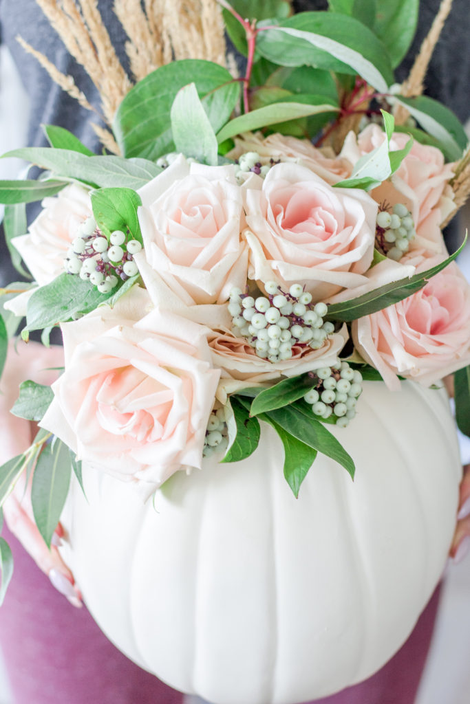 Closeup of pink roses and foliage in pumpkin vase