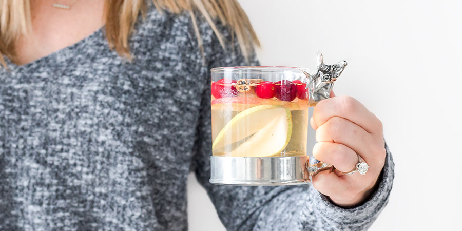 Woman in grey sweater holding sangria in glass