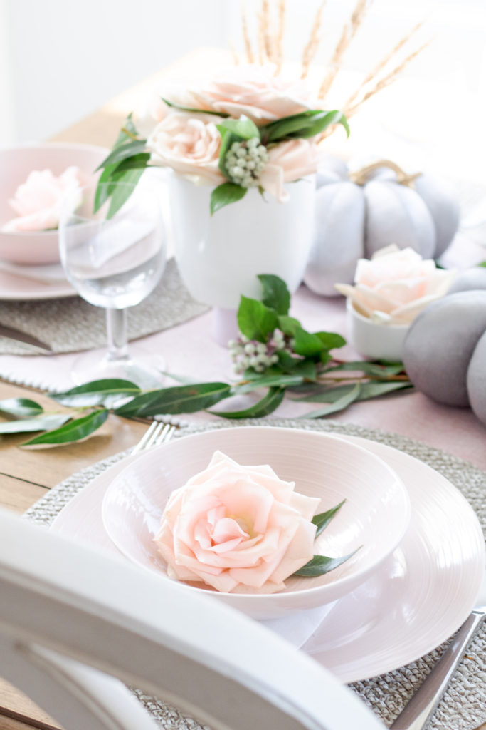 Fall table setting with pink plates and blush rose and foliage arrangements 