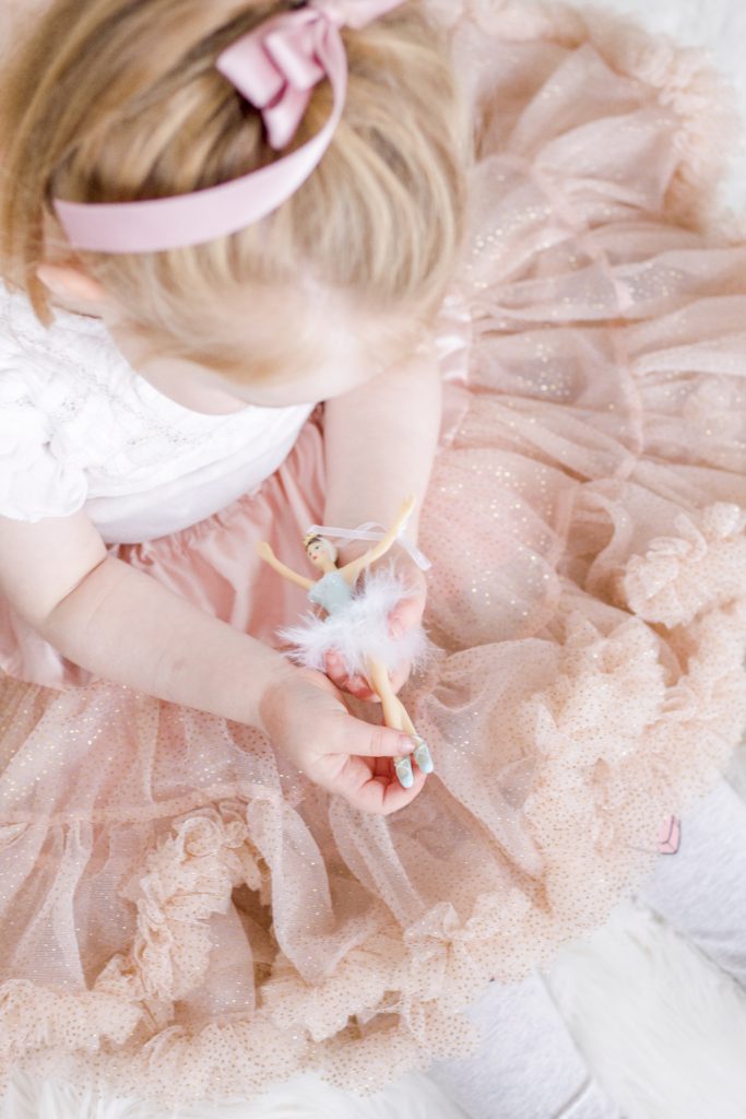 Girl in pink ballerina tutu holding ballerina Christmas ornament