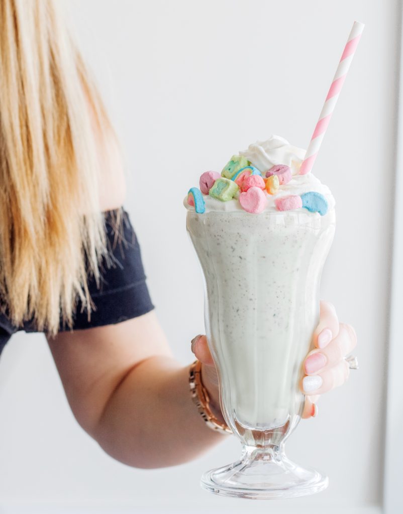 Hand holding boozy milkshake with Lucky Charms