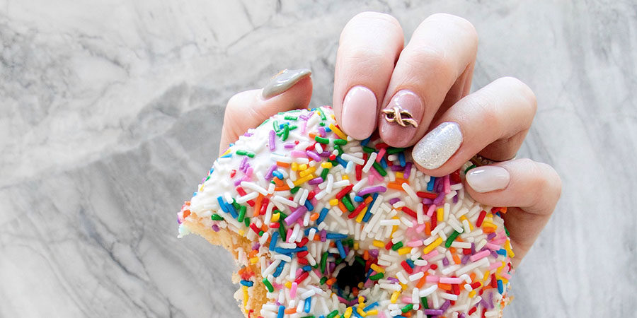 Closeup of pretty in pink nail design with a donut
