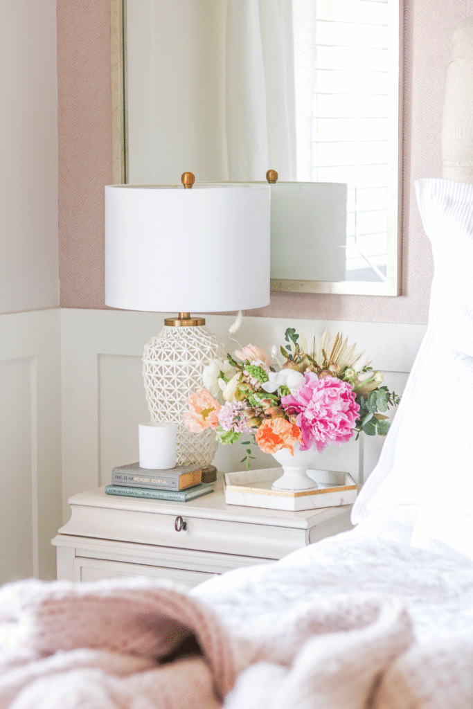 Pink and white bedroom bedside table with ornate white lamp