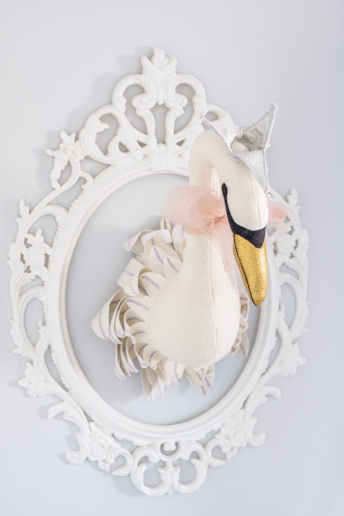 Stuffed faux swan head in white antique frame in baby girl pink peony nursery