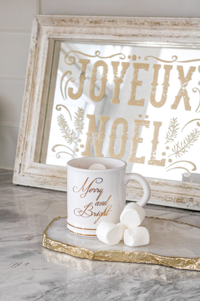 Hot cocoa with marshmallows on white kitchen countertop with Noel mirror