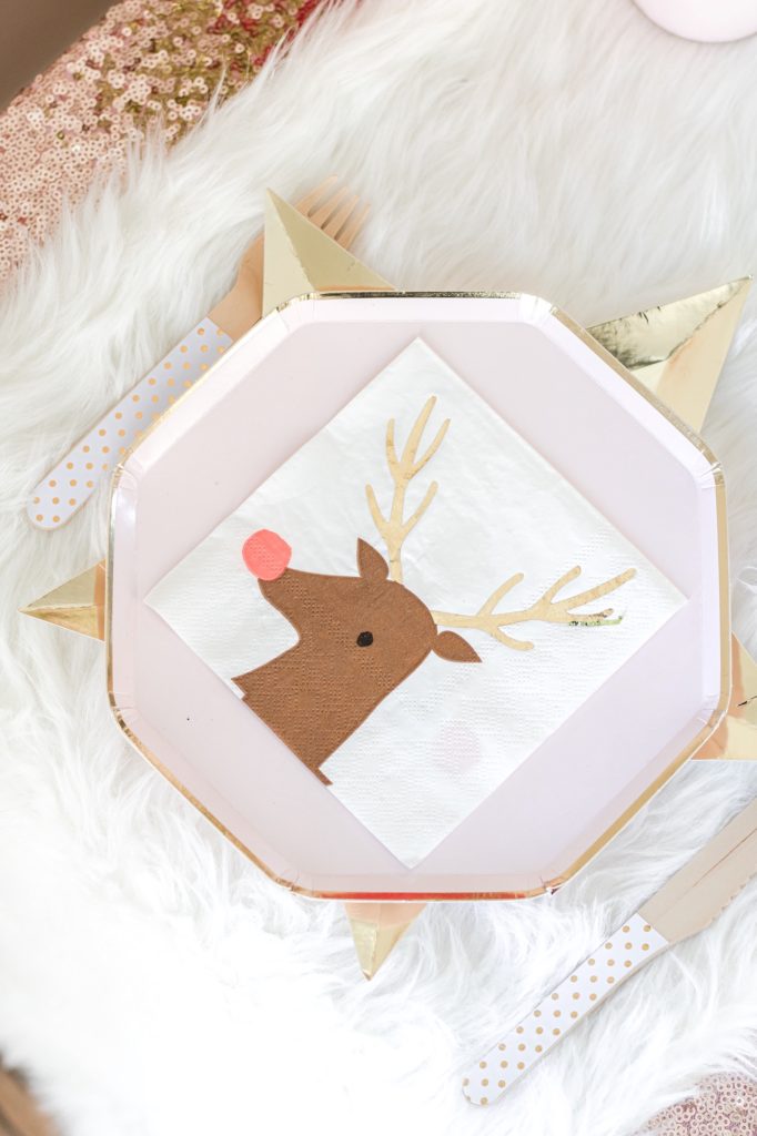 Closeup of Christmas dessert table with star charger plate, pink paper plate and reindeer napkin
